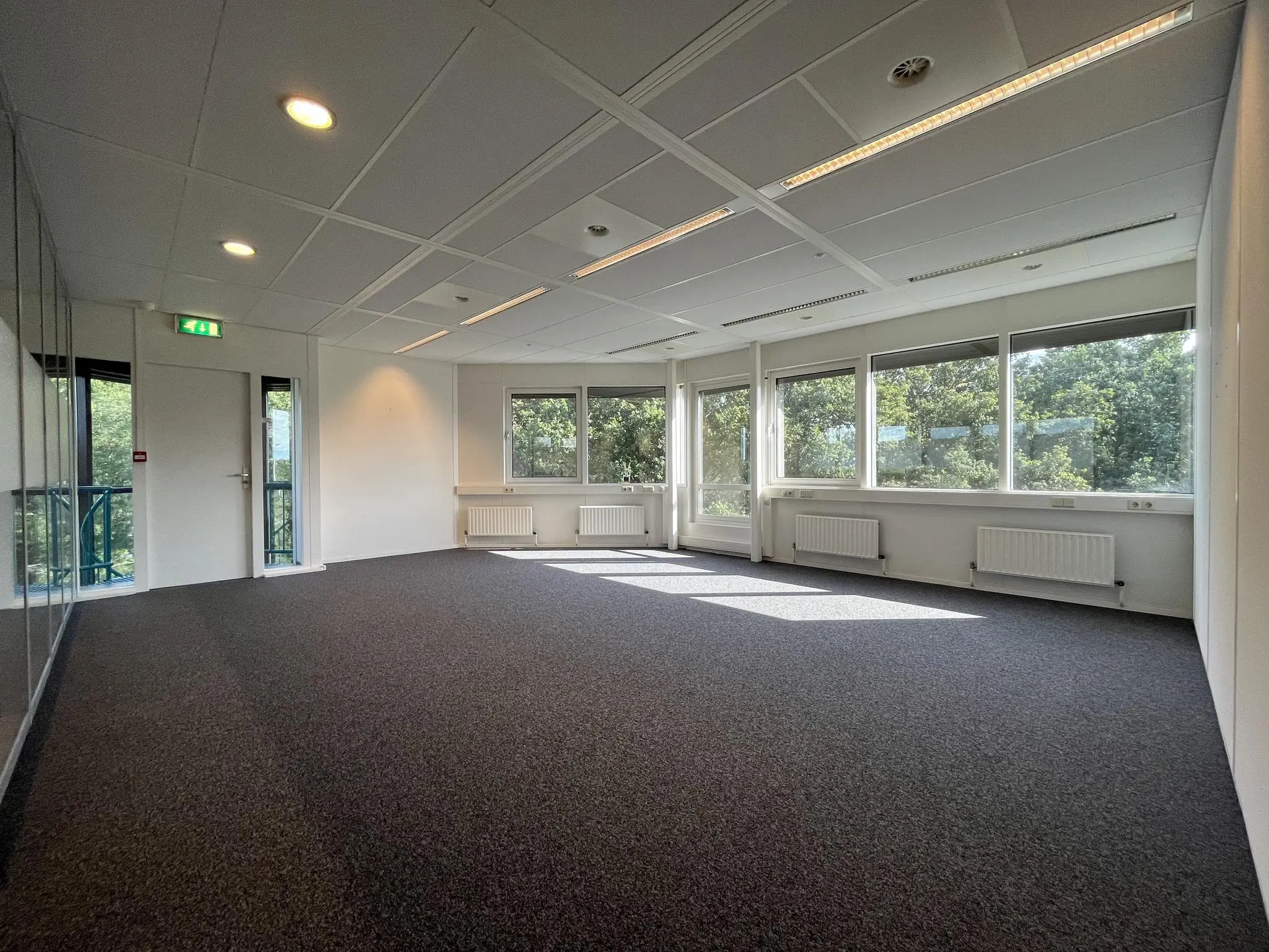 Lichte, leegstaande kantoorruimte aan de Baarnsche Dijk met grote ramen en uitzicht op groen.